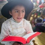 A young girl holding the Quechua Language Bible.