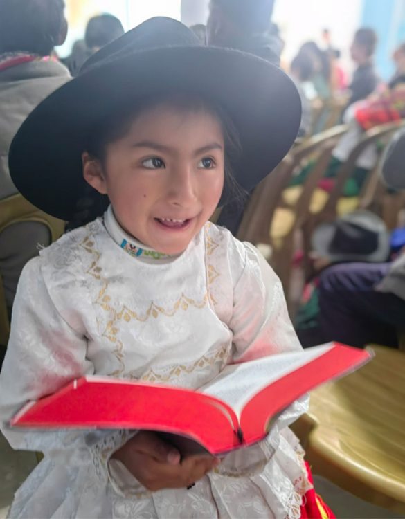 A young girl holding the Quechua Language Bible.
