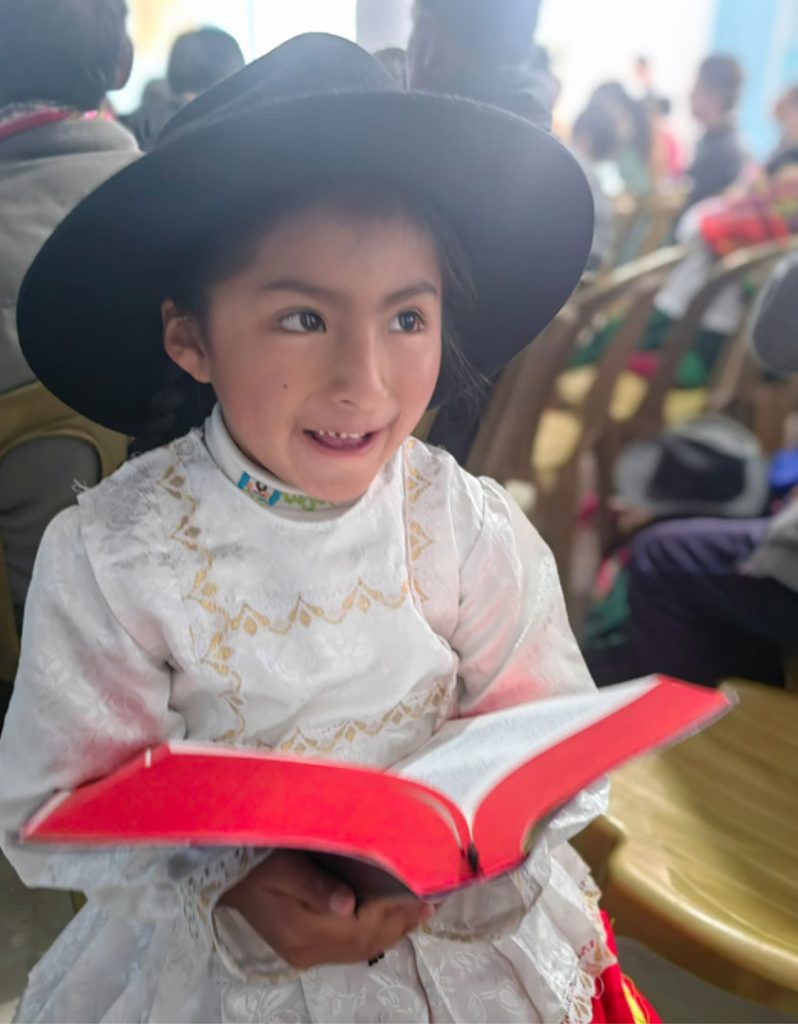 A young girl holding the Quechua Language Bible.